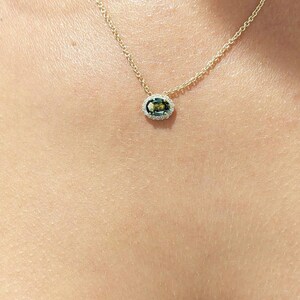 May include: A gold chain necklace with a green oval gemstone pendant surrounded by a halo of smaller diamonds.