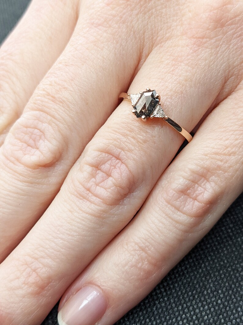 May include: A rose gold ring with a hexagonal brown diamond and two smaller triangular diamonds on the band.