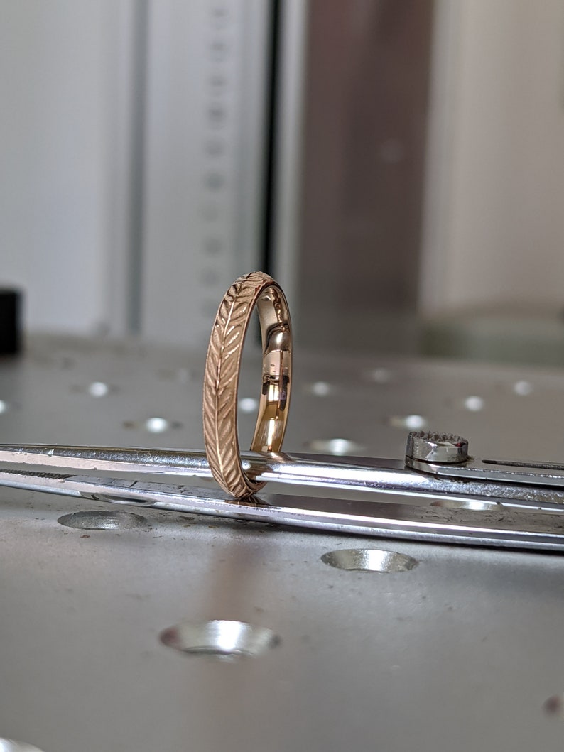 K&ouml;nnte beinhalten: Ein d&uuml;nner Goldring mit einem Blattmotiv, das um den gesamten Ring graviert ist.