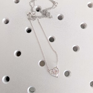 Puede incluir: Un collar de cadena de plata con un colgante en forma de coraz&oacute;n con una piedra transparente y brillante.