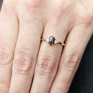 May include: A rose gold ring with a brown, octagon-shaped gemstone and two smaller, white gemstones on either side.