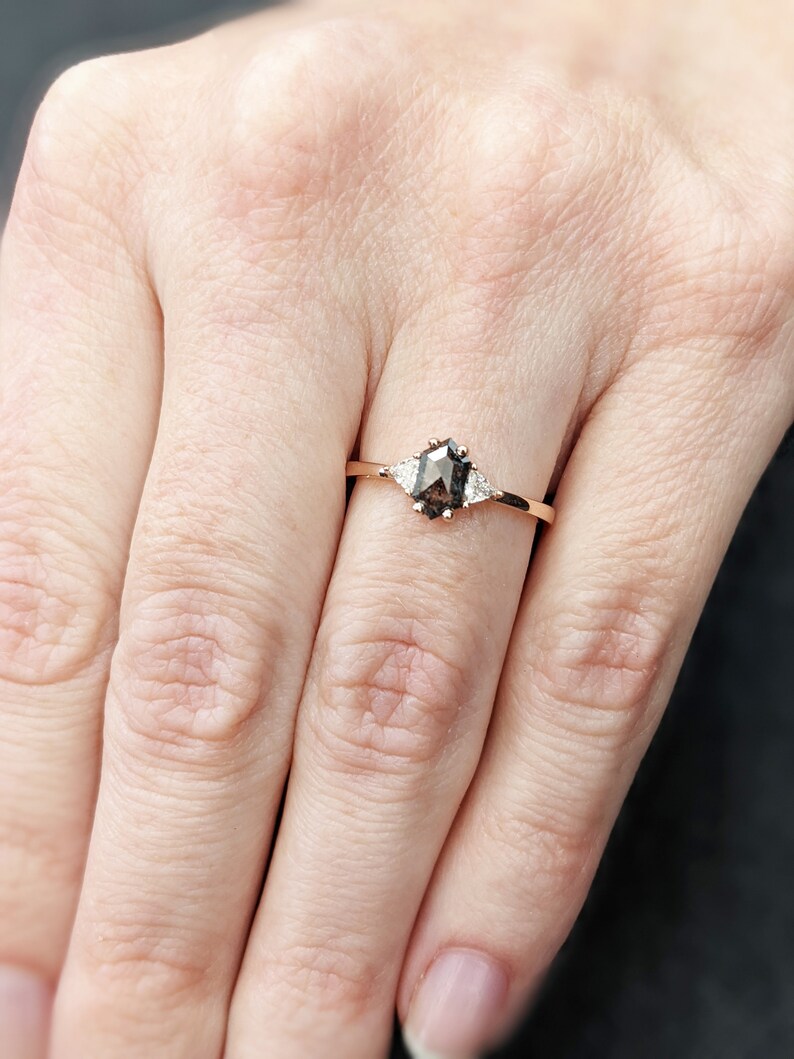 May include: A rose gold ring with a brown, octagon-shaped gemstone and two smaller, white gemstones on either side.
