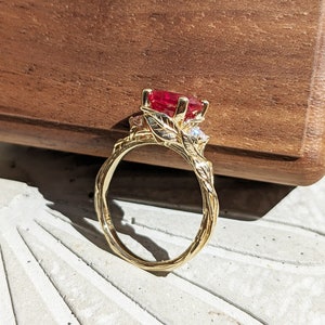 May include: A gold ring with a ruby and diamond accents. The ring features a twisted band with leaf details.