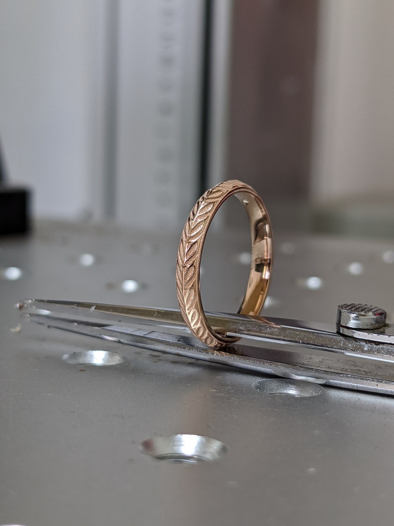 K&ouml;nnte beinhalten: Ein Goldring mit einem eingravierten Blattmotiv.