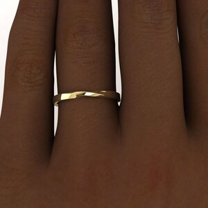 May include: A simple gold band ring with a twisted design. The ring is worn on a finger.