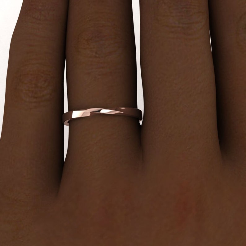 Puede incluir: Un anillo de banda de oro rosa con un dise&ntilde;o retorcido. El anillo se lleva en un dedo.