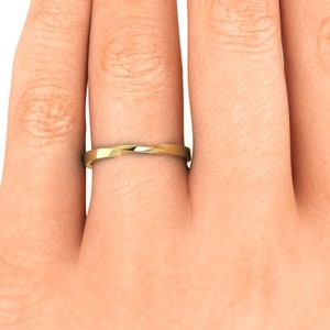 May include: A simple gold wedding band with a twisted design.