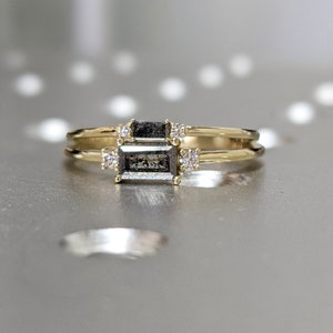 May include: A gold ring with a black emerald-cut gemstone and smaller diamonds on the band.