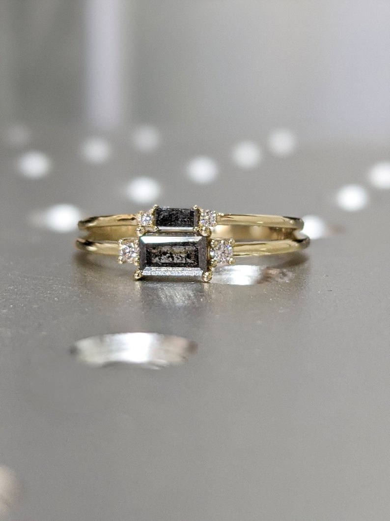 May include: A gold ring with a black emerald-cut gemstone and smaller diamonds on the band.
