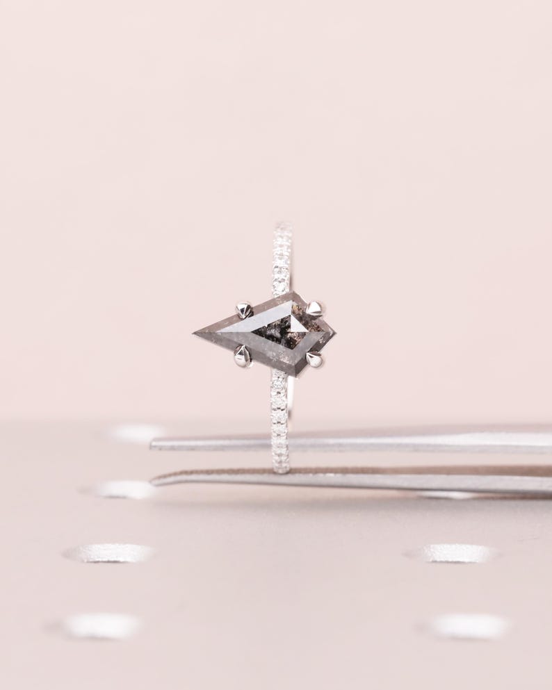 Puede incluir: Un anillo de plata con un diamante &uacute;nico en forma de cometa, sal y pimienta. La banda del anillo est&aacute; adornada con peque&ntilde;os diamantes brillantes. El diamante est&aacute; sujeto por cuatro garras de plata. Una pieza de joyer&iacute;a fina.