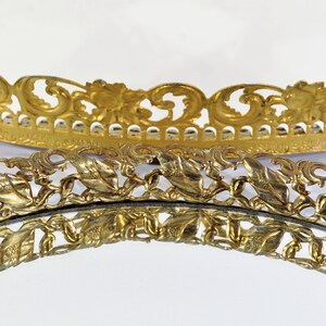 Puede incluir: Dos bandejas redondas decorativas de color dorado con intrincados y ornamentados recortes en forma de hoja alrededor de los bordes.