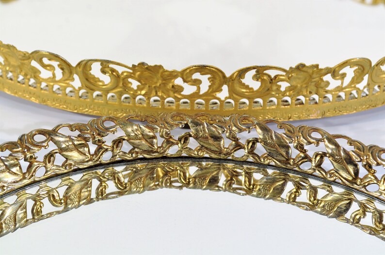 Puede incluir: Dos bandejas redondas decorativas de color dorado con intrincados y ornamentados recortes en forma de hoja alrededor de los bordes.