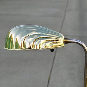 May include: A gold-toned floor lamp with a curved, ribbed shade. The lamp has a simple, elegant design.