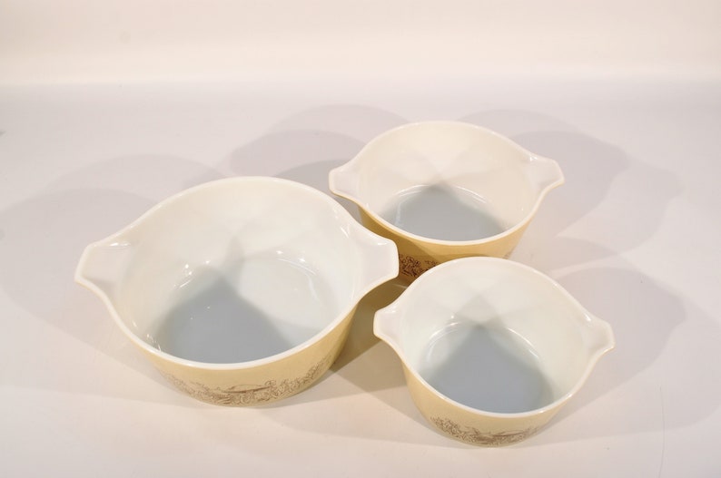 K&ouml;nnte beinhalten: Set aus drei wei&szlig;en R&uuml;hrsch&uuml;sseln mit einem braunen und gelben Blumenmuster. Die Sch&uuml;sseln sind ineinander verschachtelt.