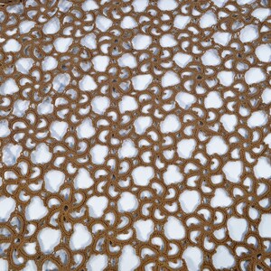 May include: A close-up of a brown crocheted lace fabric with a repeating pattern of flowers. The fabric is delicate and intricate, with a light brown color.