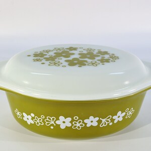 May include: A green casserole dish with a white lid. Both the dish and lid have a floral pattern in white and green.