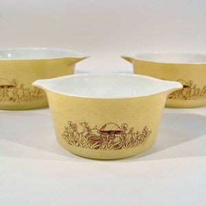 K&ouml;nnte beinhalten: Set aus drei gelben Pyrex-Sch&uuml;sseln mit einem braunen Pilz- und Blumendesign.