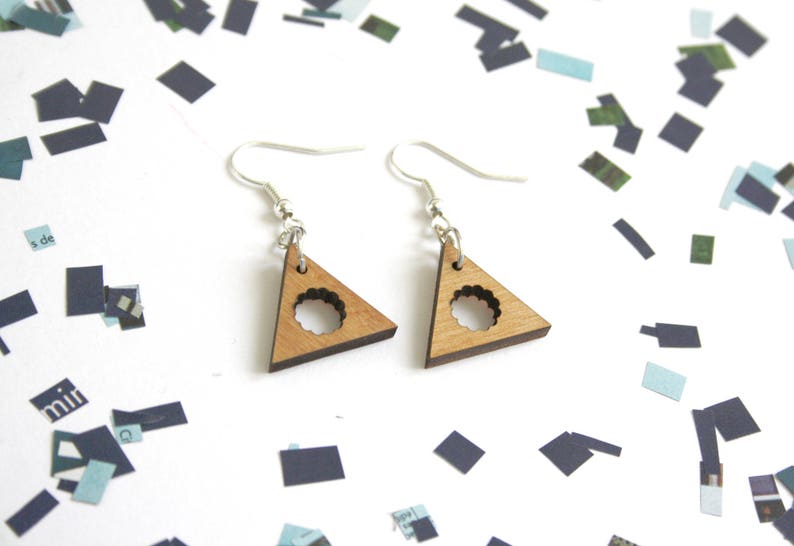 May include: A pair of wooden triangle earrings with a circular cutout. The earrings are silver and have a simple design.