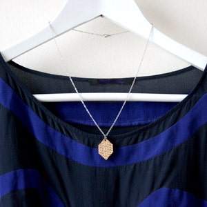 May include: A black and blue sleeveless dress with a geometric pattern and a silver chain necklace with a wooden pendant.