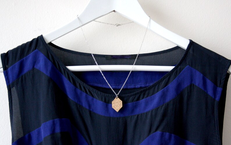 May include: A black and blue sleeveless dress with a geometric pattern and a silver chain necklace with a wooden pendant.