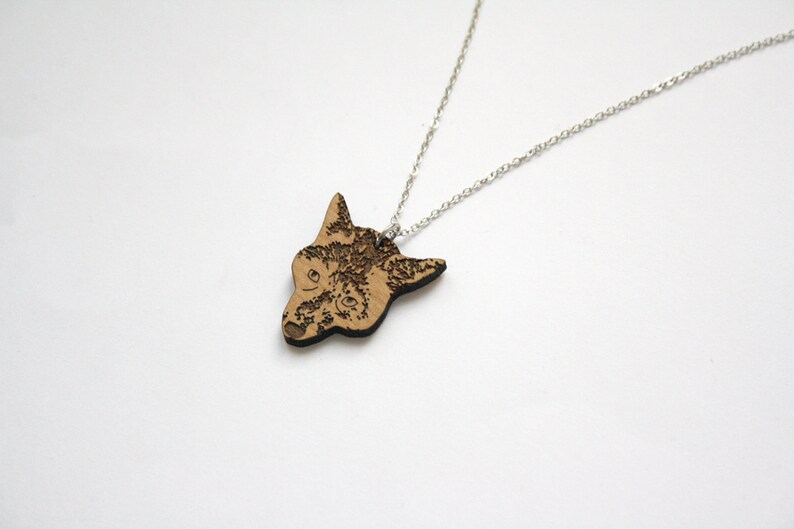 May include: A silver chain necklace with a wooden pendant featuring a detailed laser-engraved image of a wolf's head.