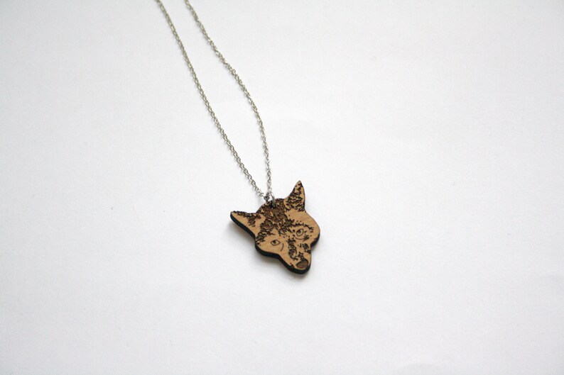 May include: A silver chain necklace with a wooden pendant featuring a detailed laser-engraved wolf head.