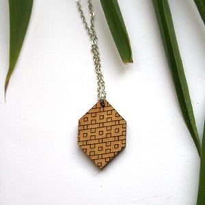 May include: A silver chain necklace with a hexagonal wooden pendant featuring a geometric pattern.