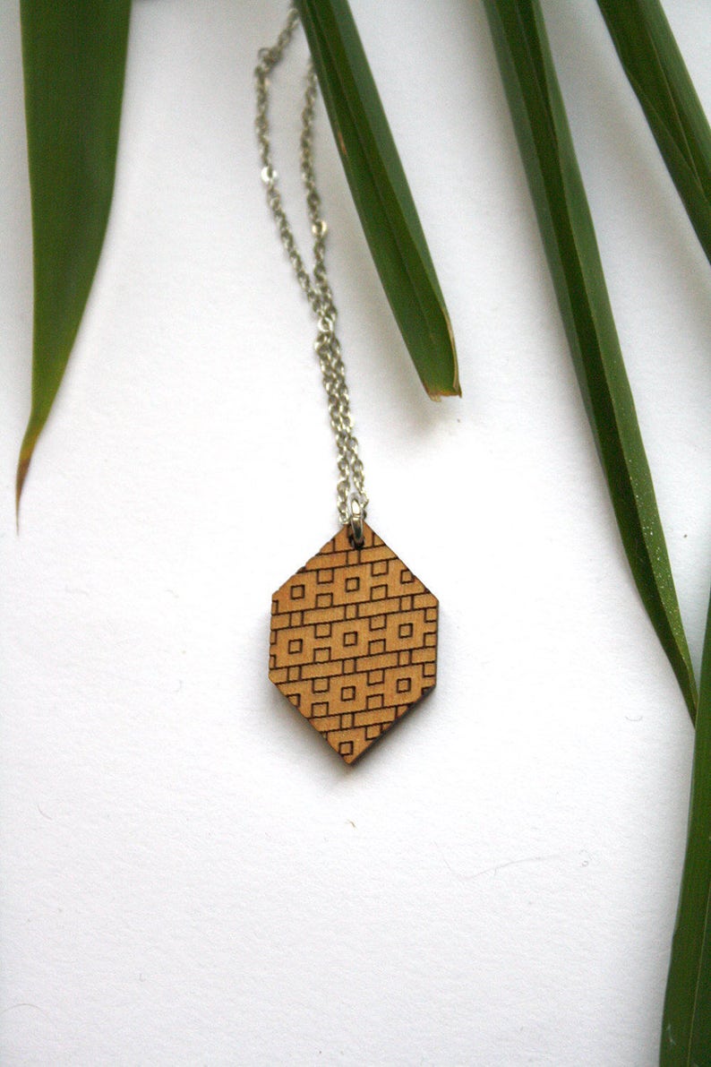 May include: A silver chain necklace with a hexagonal wooden pendant featuring a geometric pattern.