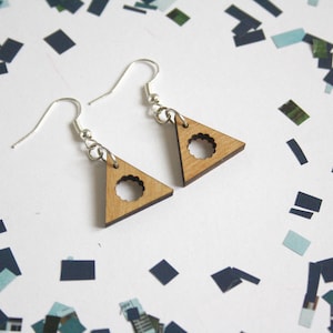 May include: A pair of silver earrings with wooden triangle pendants. The triangles have a circular cutout in the center.