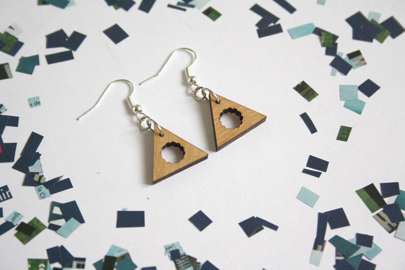 May include: A pair of silver earrings with wooden triangle pendants. The triangles have a circular cutout in the center.