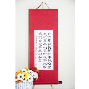 Può includere: Un rotolo rosso con calligrafia nera in caratteri cinesi. Il rotolo è appeso a un supporto in legno. Il testo recita: "Dovete temere il Signore con sincerità e servirlo con tutto il vostro cuore. Quanto a me e alla mia casa, serviremo il Signore."