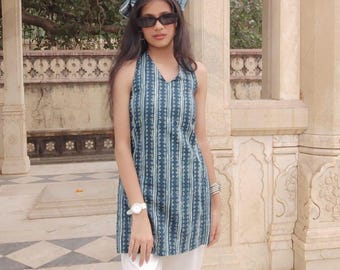 May include: A blue and white striped tunic top and matching headscarf. The tunic has a V-neck and is worn with white trousers. The outfit is accessorized with sunglasses and a white wristwatch.