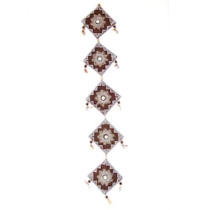 Puede incluir: Un tapiz de pared de tela marrón con cinco paneles cuadrados. Cada panel tiene un diseño de mandala blanco con un pequeño espejo redondo en el centro. Los paneles están conectados por cuerdas con pequeñas cuentas.