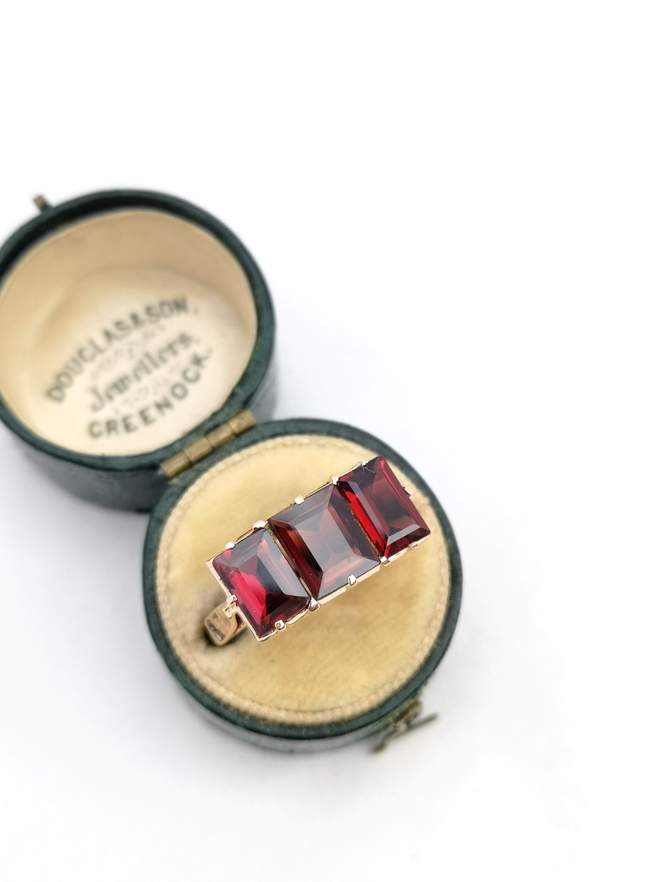 Anillo de tres piedras con granate de talla esmeralda en oro de 9 quilates