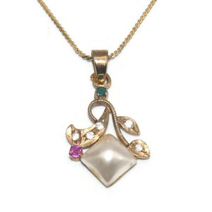 May include: A gold necklace with a pendant featuring a white pearl, a pink ruby, and green emeralds. The pendant is in the shape of a stylized flower with leaves.
