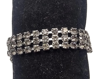 Pulsera vintage de estilo mediados de siglo de los años 50, en tono plateado y con pedrería, con cierre de clip articulado.