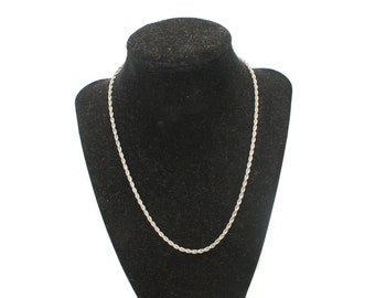 May include: A silver rope chain necklace displayed on a black velvet bust form.