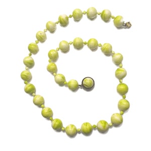 Tom dourado vintage com colar de contas de acrílico marmorizado verde e branco.