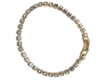 Vintage goudkleurige en kristalheldere strass tennisarmband met scharnierende clipsluiting.