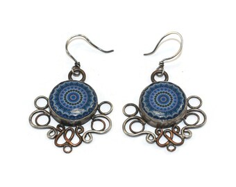 May include: A pair of silver earrings with blue and purple mandala designs. The earrings have a silver wire design with copper accents.