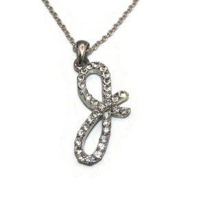 Puede incluir: Un collar de plata con un colgante en forma de la letra J. El colgante está cubierto de diamantes de imitación transparentes.