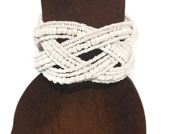 May include: White beaded bracelet with a woven design. The bracelet is made of many strands of small white beads.