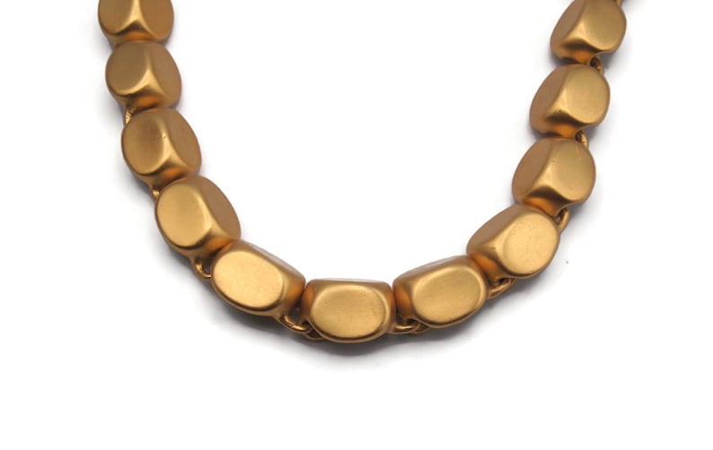 May include: A gold necklace with large, oval-shaped beads. The beads are matte and have a slightly textured surface.