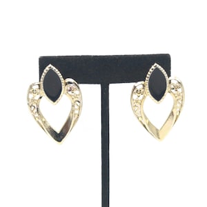 May include: A pair of gold-tone earrings with black heart-shaped accents. The earrings feature a delicate filigree design and a black marquise-shaped stone in the center.