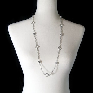 May include: A silver chain necklace with clear square and round beads.