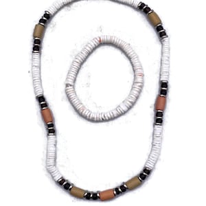May include: A white beaded necklace and bracelet set. The necklace features alternating sections of white beads, brown, tan, and peach-colored cylindrical beads, and small black beads. The bracelet mirrors the white bead design.