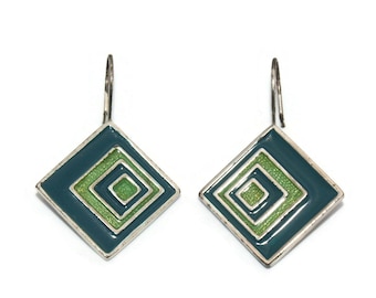 Puede incluir: Un par de pendientes colgantes de plata con un diseño geométrico azul verdoso y verde. Los pendientes tienen una forma cuadrada con cuadrados concéntricos en el interior.