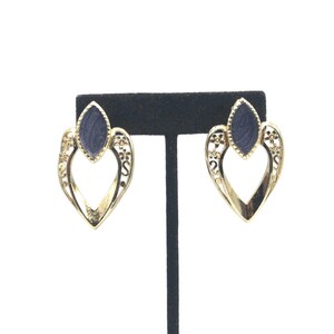 May include: A pair of gold heart-shaped earrings with a dark blue stone in the center of each heart.