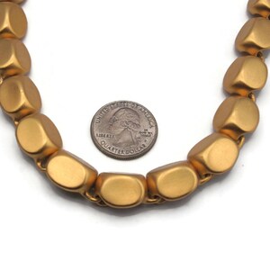 May include: A gold necklace made of large, rounded, matte beads. The beads are about the size of a US quarter.