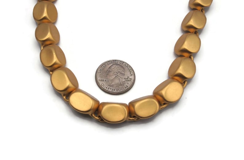 May include: A gold necklace made of large, rounded, matte beads. The beads are about the size of a US quarter.